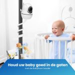 Een witte babyfoonhouder met zwanenhals, bevestigd aan een staande paal. Een lachende baby in een babybedje op de achtergrond.